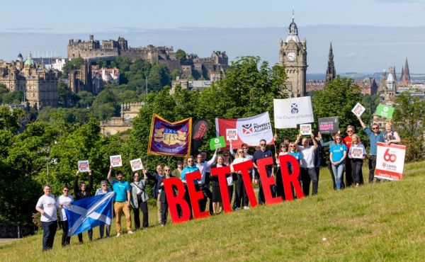 Charities, organisation and groups joined together to launch Scotland Demands Better. Image shows representatives on Calton Hill in Edinburgh with a sign saying 'better'.